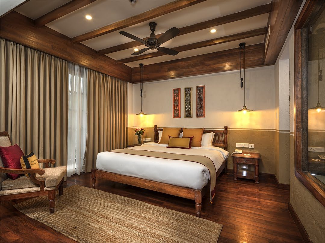 The Executive Suite bedroom, its king bed framed by carved Newari panels and brass pendant lights