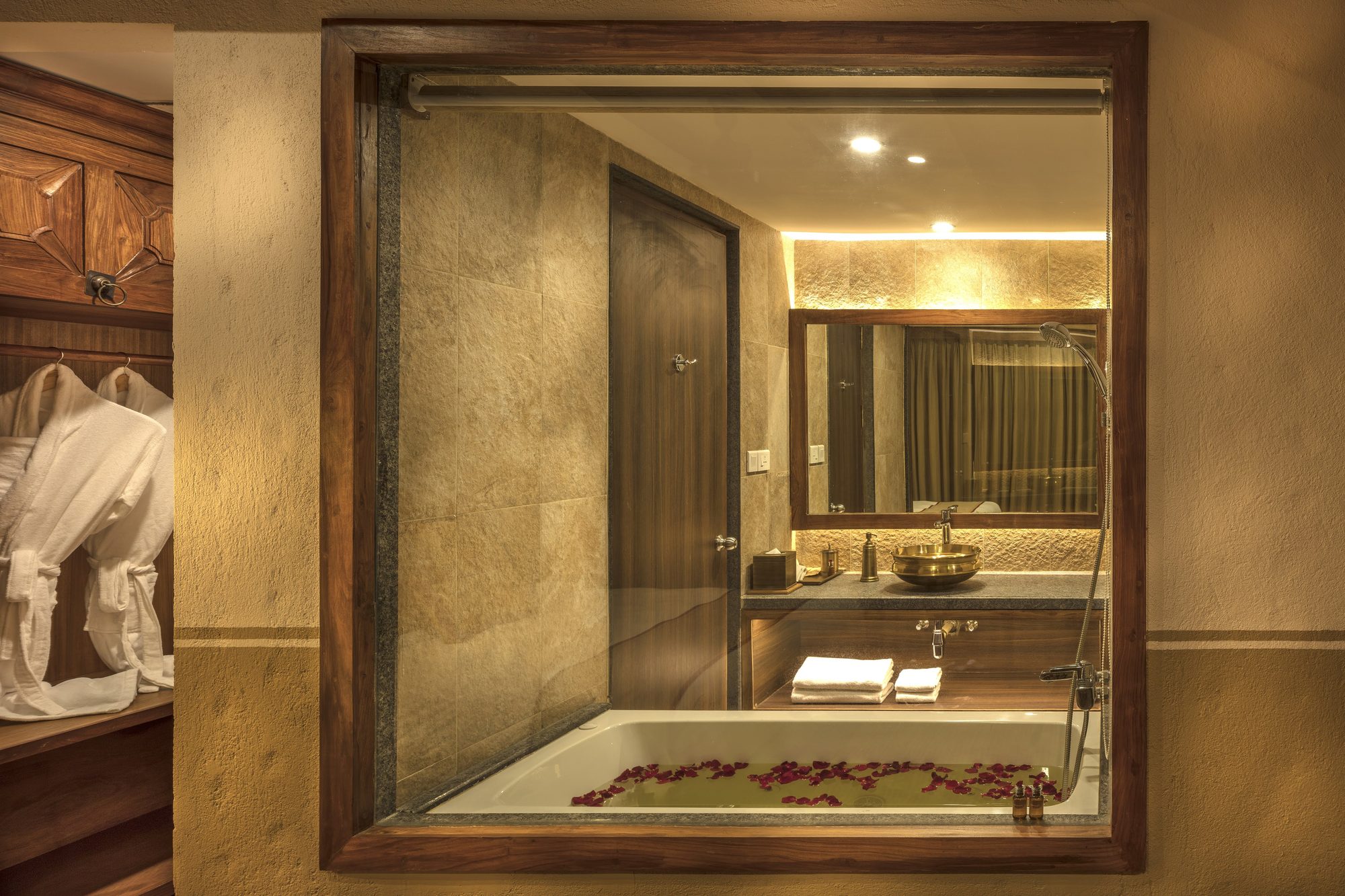 The Executive Suite Jacuzzi set with rose petals, seen through the carved timber window from the dressing area