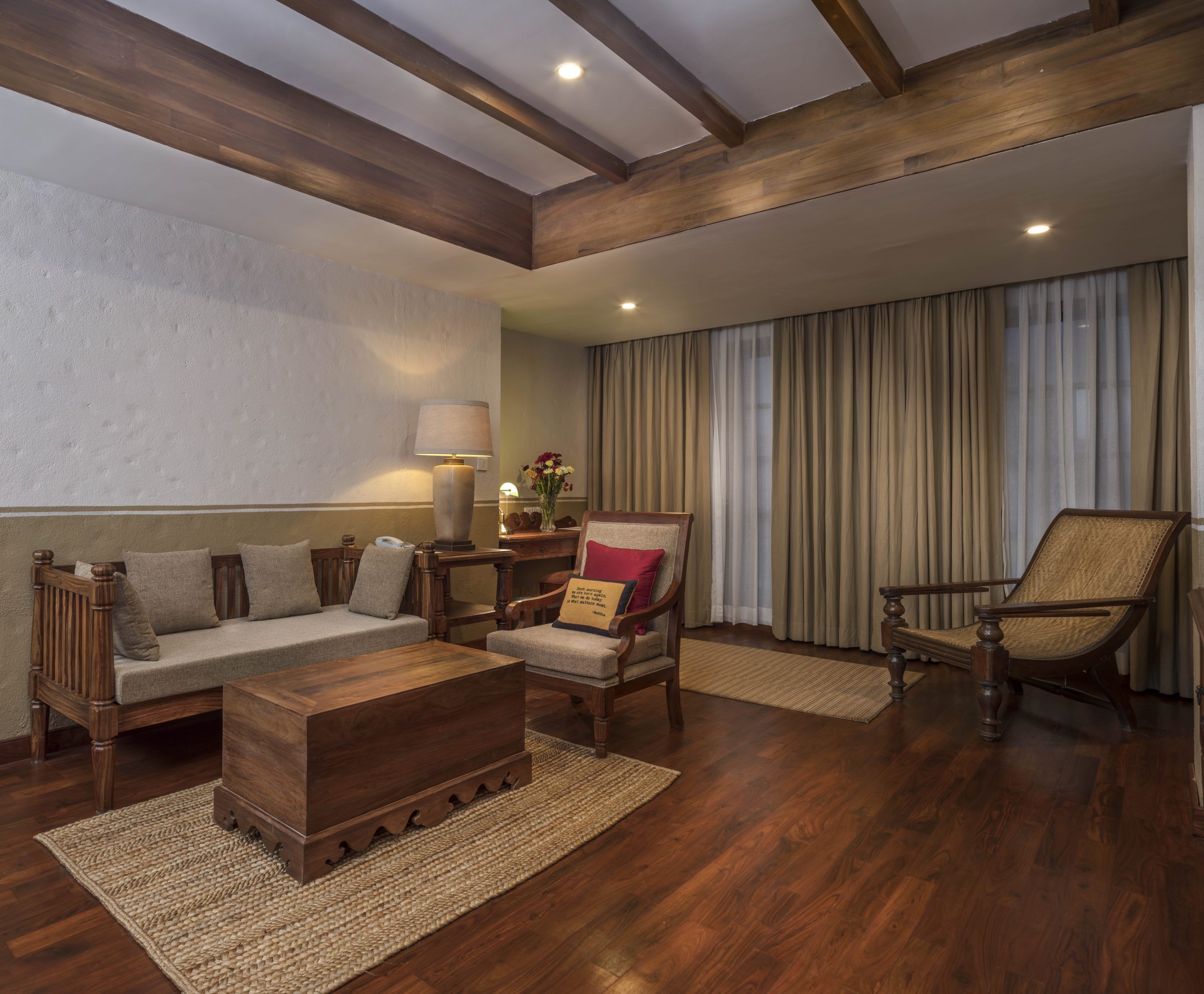 The separate living room of the Executive Suite, with a timber-beamed ceiling and a caned planter’s chair by the window