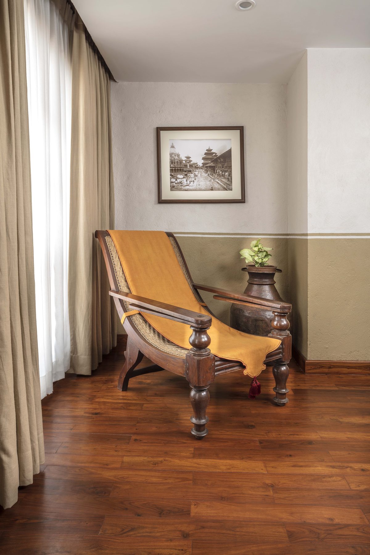 A caned planter’s chair by the window of the Executive Suite, beside an archival photograph of Kathmandu