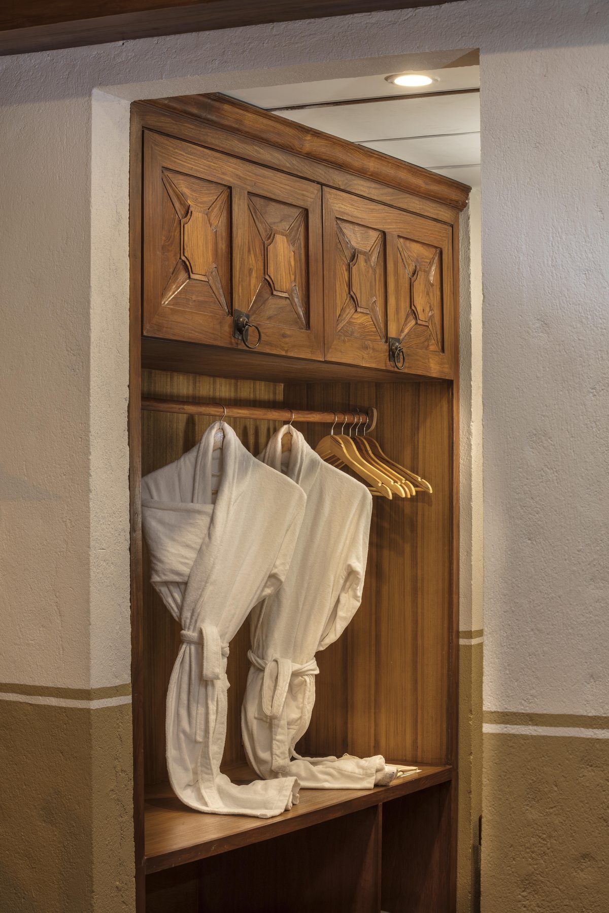 The carved timber wardrobe of the Executive Suite, hung with bathrobes